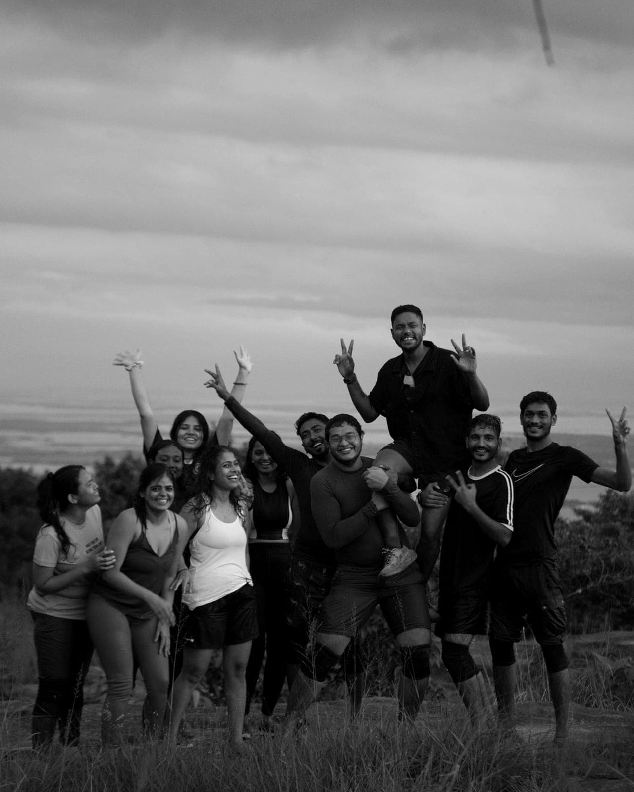 A group celebrating outdoors with their arms raised