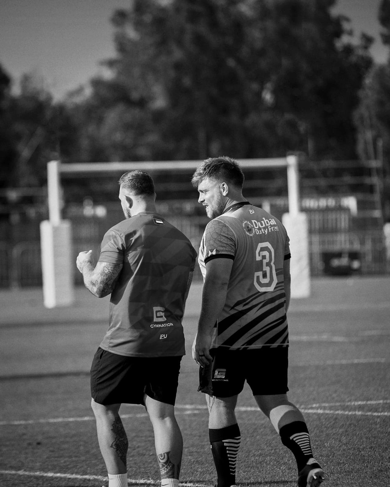 Two players in numbered team kit on a sports field